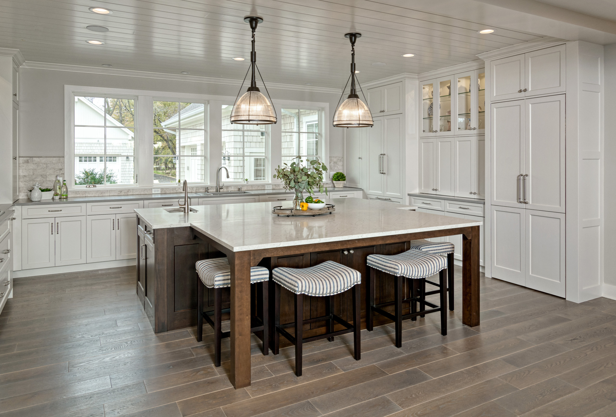Spacious kitchen with large island, white cabinetry, and pendant lighting.