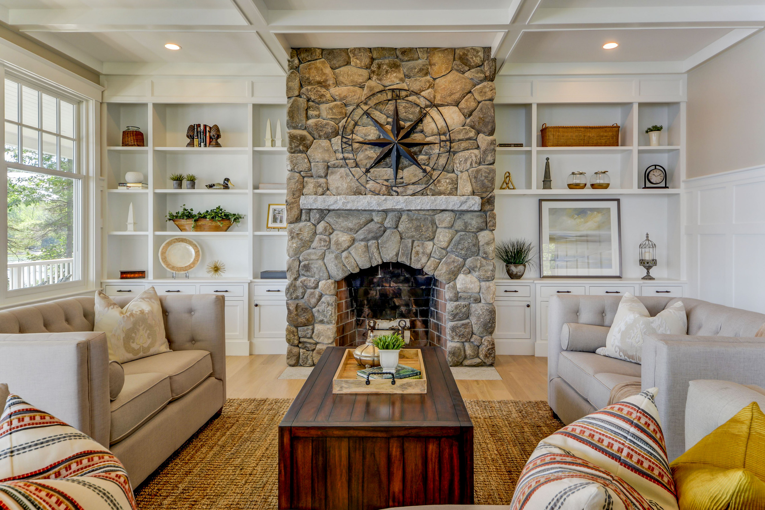 Rustic stone fireplace with built-in shelves in a cozy living room.