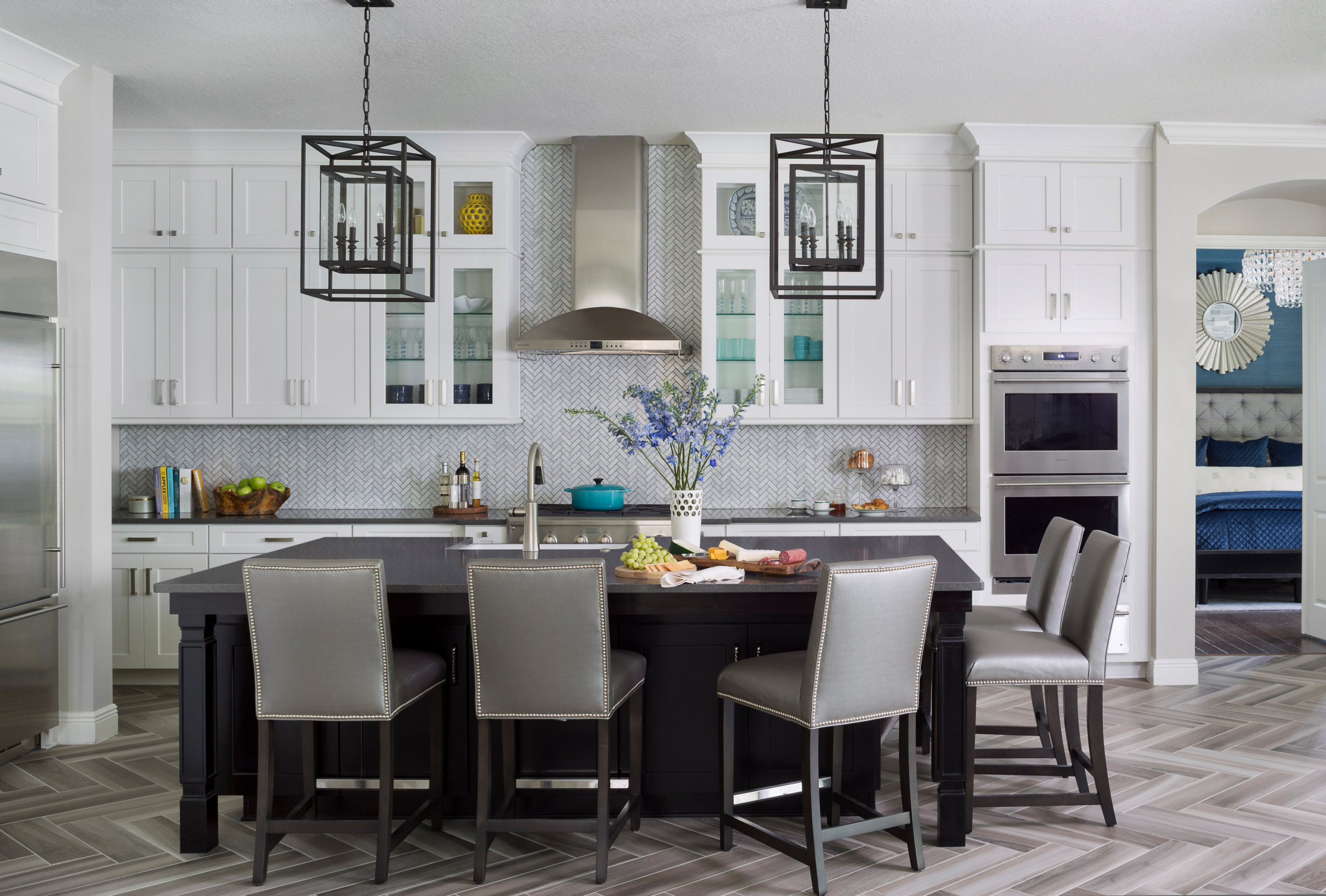 Modern open-concept kitchen with white cabinetry, black island, and stainless steel appliances.