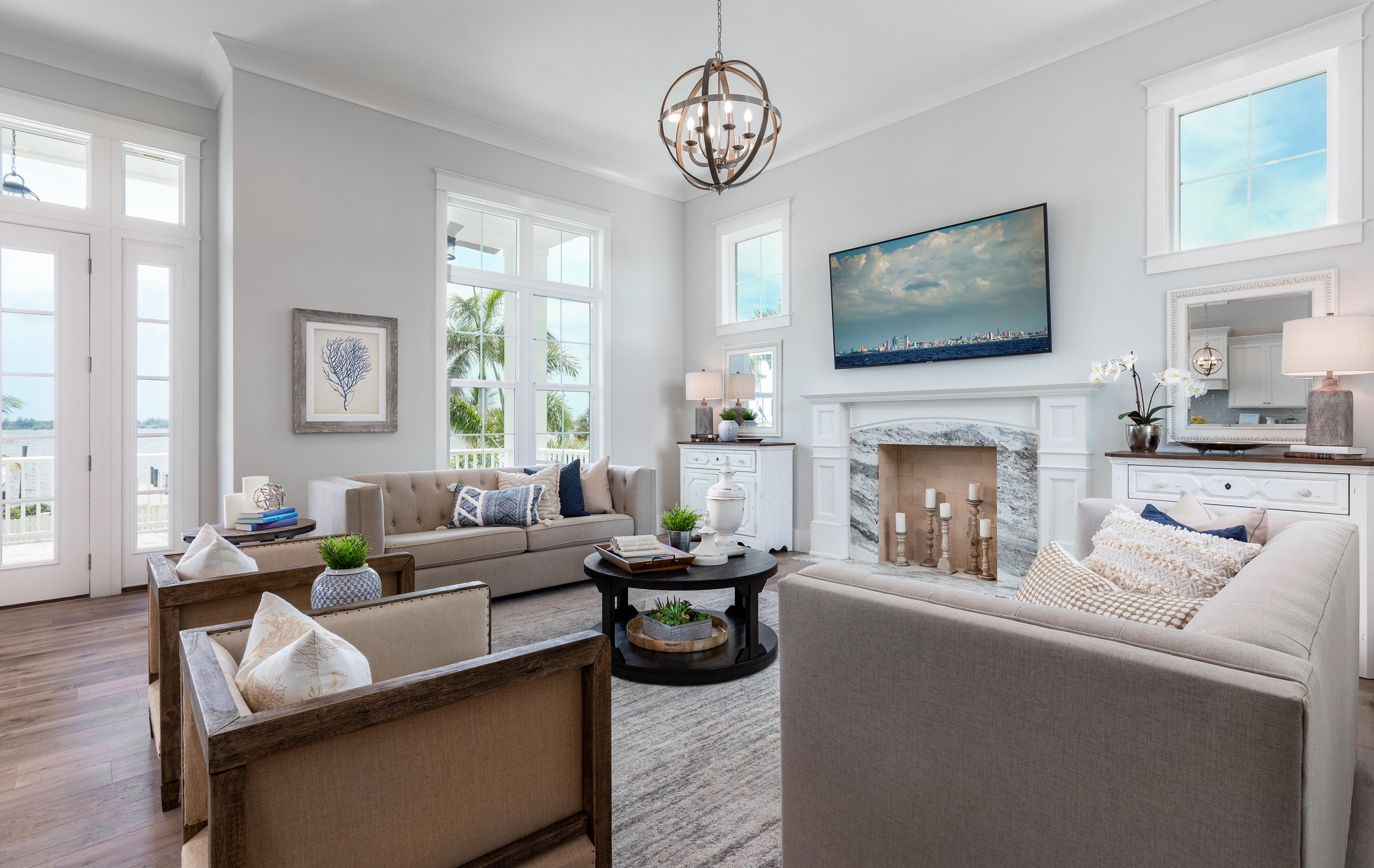 Bright coastal living room with marble fireplace and large windows