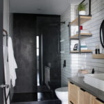 Modern bathroom with sleek black and white design, featuring hexagonal tiles, open shelving, and a minimalist aesthetic.