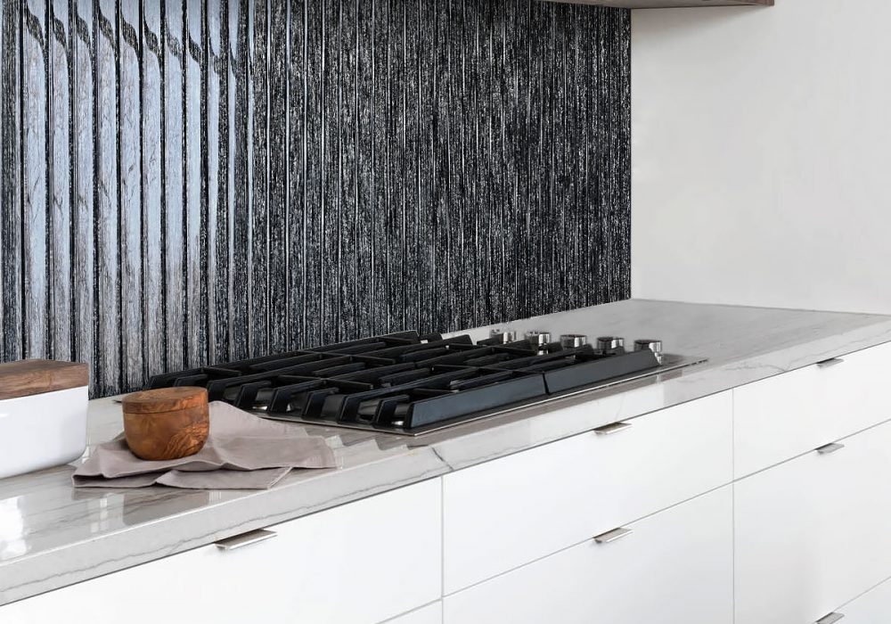 Contemporary kitchen featuring vertical shimmery black glass backsplash tiles, white lower cabinets, and wood upper cabinets